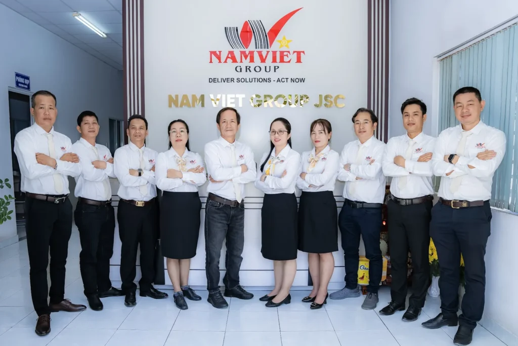 Tập thể văn phòng Nam Việt Group trước logo công ty