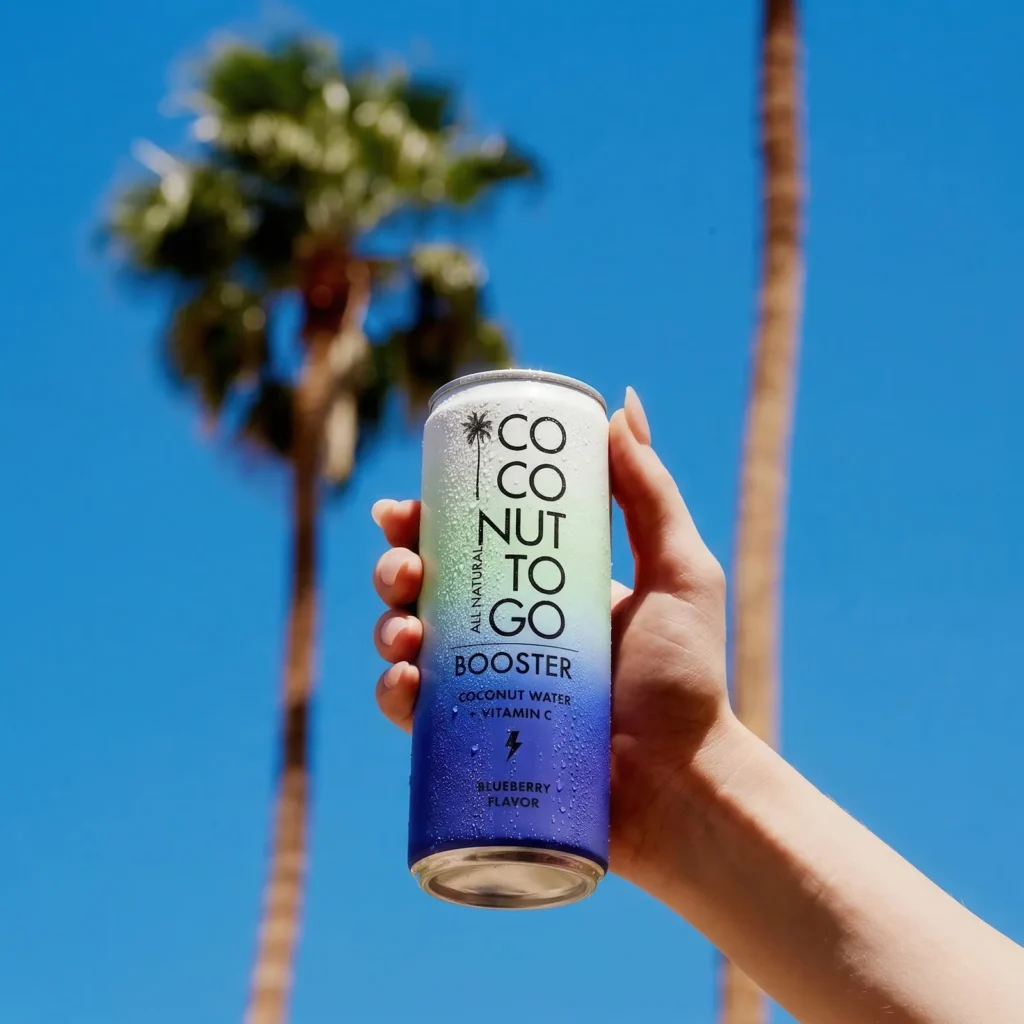 Tay cầm lon Coconuttogo dưới bầu trời xanh và hàng dừa